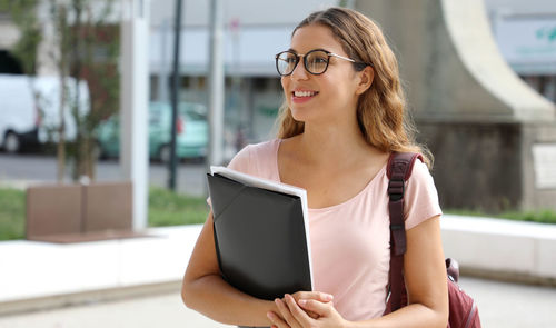 Smiling young woman looking away while standing outdoors