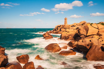 Rocks by sea against sky