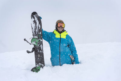 Happy male hiker with snowboard in deep powder snow