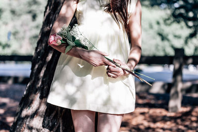 Midsection of bride holding rose