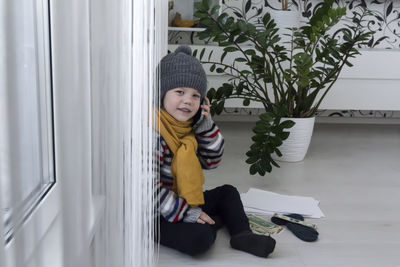 A small child with a yellow scarf near the radiator speaks on the phone.  energy crisis concept
