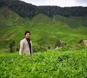 Portrait of young man standing at tea plantation