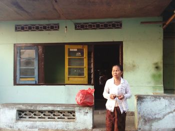 Mature woman standing outside house