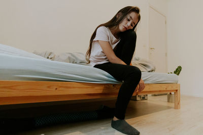 Sleeping girl sitting on the bed in the room.