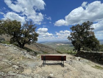 Empty bench on landscape against sky
