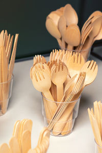 Rounded forks in plastic cups, wooden disposable cutlery.