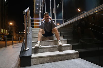 Thoughtful young man sitting on staircase at night