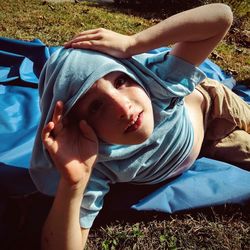 Portrait of boy lying on blanket at field