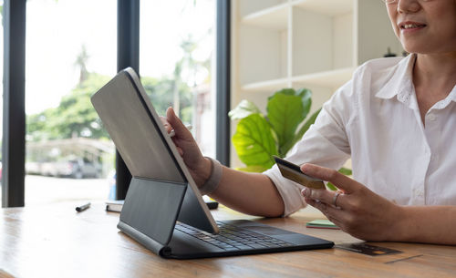 Midsection of man using mobile phone while sitting on table