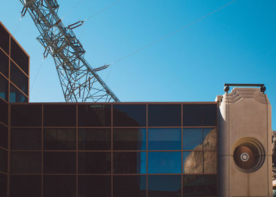 Building by electricity pylon against sky