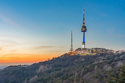 Communications tower and buildings against sky during sunset