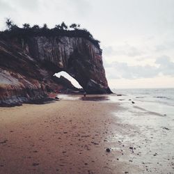 Rock formation by sea against sky