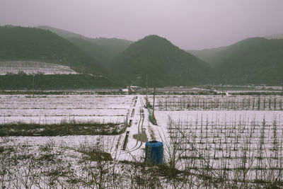 Wooden posts on field by mountains against sky