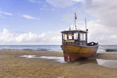 Ship moored on beach against sky