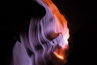 Low angle view of illuminated lighting equipment against black background