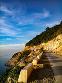 Road by sea against blue sky