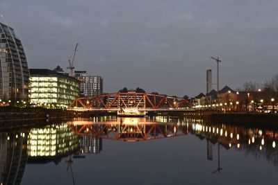 Reflection of illuminated buildings in river against sky