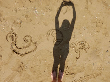 Shadow of person on heart shape on sand at beach