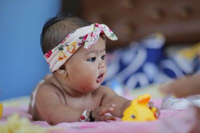 Cute baby girl lying on bed at home