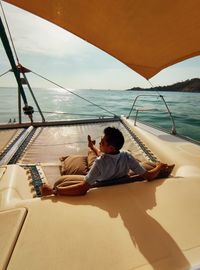 Man sitting on boat in sea against sky
