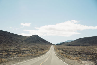 Road leading towards mountains against sky