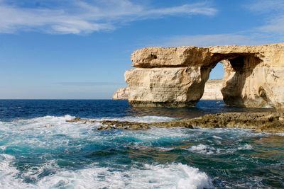 Scenic view of rock formation in sea against sky