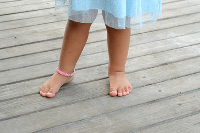 Low section of girl standing on wooden floor