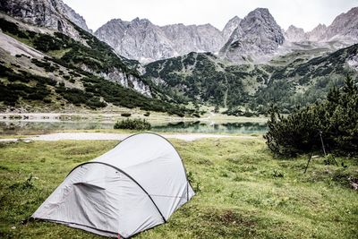 Tent by lake against mountains