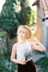 Portrait of young woman standing against trees