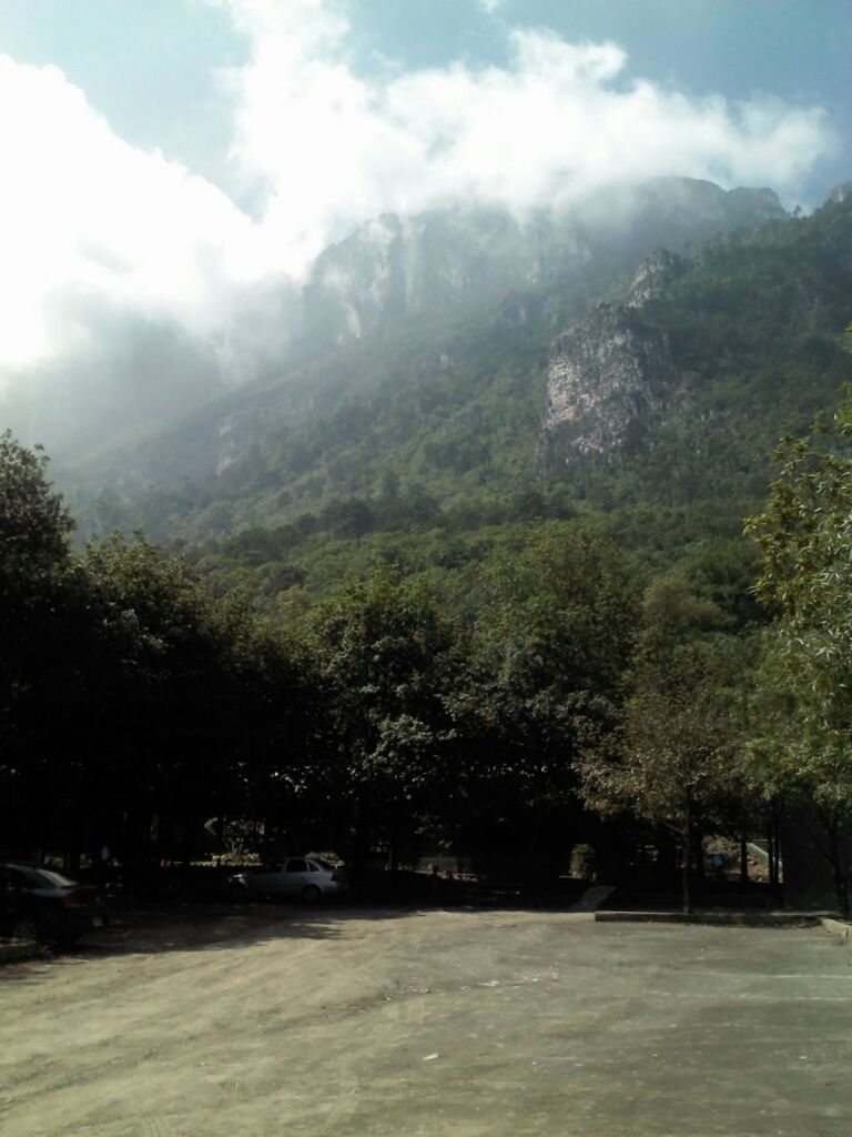 tree, mountain, sky, road, cloud - sky, beauty in nature, nature, transportation, scenics, tranquility, tranquil scene, cloud, cloudy, built structure, building exterior, architecture, street, sunlight, the way forward, landscape