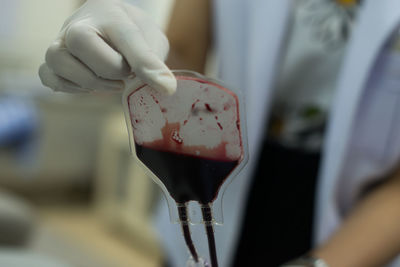 Midsection of doctor holding blood samples at hospital