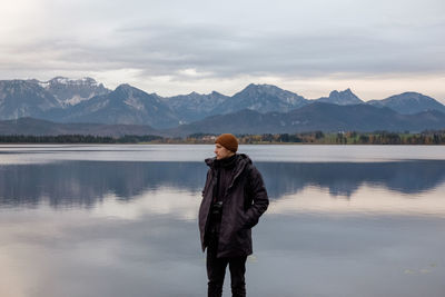 Rear view of man looking at lake against mountains