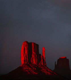 Red rock formation on mountain against sky at night