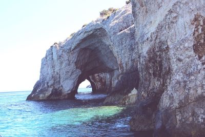 Rock formation by sea against sky