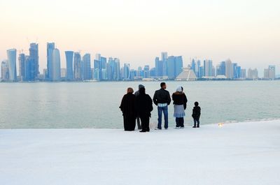 Rear view of family standing by river at mia park against city