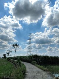 Road amidst field against sky