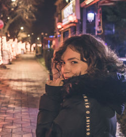 Portrait of young woman in city at night