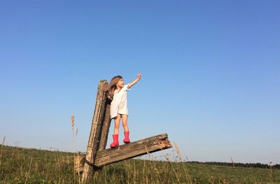 Low angle view of woman standing on field against clear sky