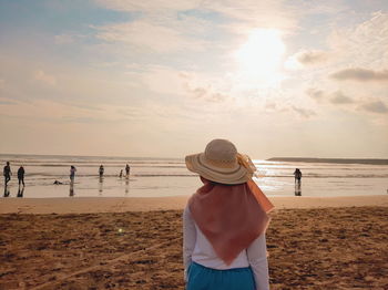 Woman standing on beach against sea against sky