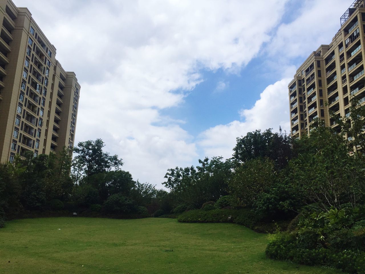 architecture, building exterior, built structure, tree, sky, grass, city, cloud, lawn, cloud - sky, day, outdoors, tranquility, tranquil scene, growth, green color, cloudscape, nature, apartment, park, scenics, no people, tall - high, beauty in nature, green, garden