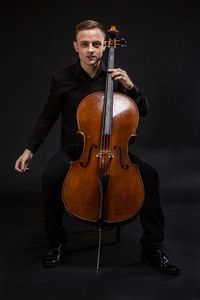 Portrait of man playing cello against gray background