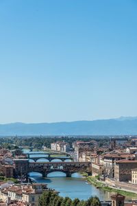 Ponte vecchio over arno river against blue sky in city