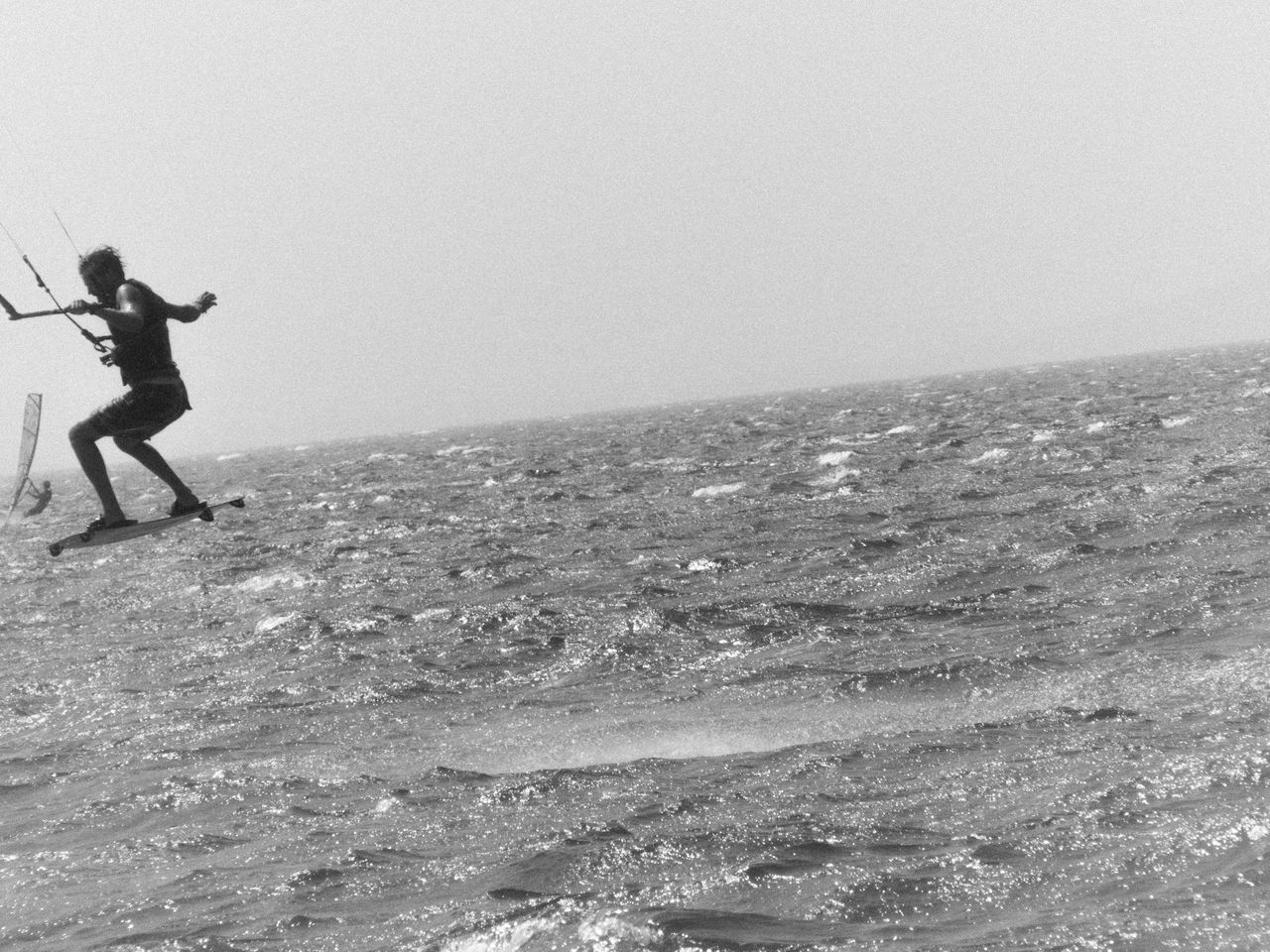 MAN SURFING ON BEACH AGAINST SKY