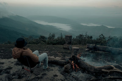 A man is sitting on the peak by the bonfire