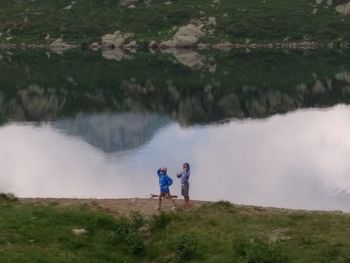 Rear view of man and woman standing by lake