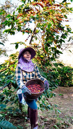 Portrait of woman standing by basket against plants