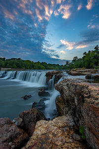 Scenic view of waterfall against sky