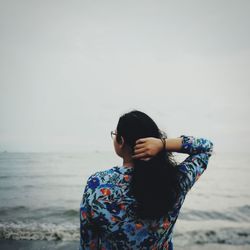 Woman standing at beach against sky