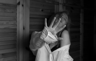 Smiling sensuous young woman standing against wooden wall