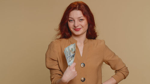 Portrait of young woman standing against pink background